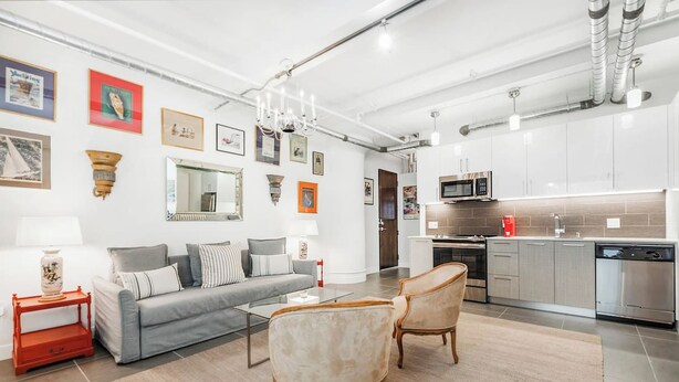 A modern kitchen with stainless steel appliances, a grey sofa, and a chandelier. - Cozy 1-bedroom Grnd Flr apt. Sleeps 4, Pool & Free Parking (Los Angeles)