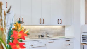 A modern kitchen with white cabinets, a built-in dishwasher, and a stainless steel sink. - Berkeley Studio by HolidayCo. (BERKELEY VALE)