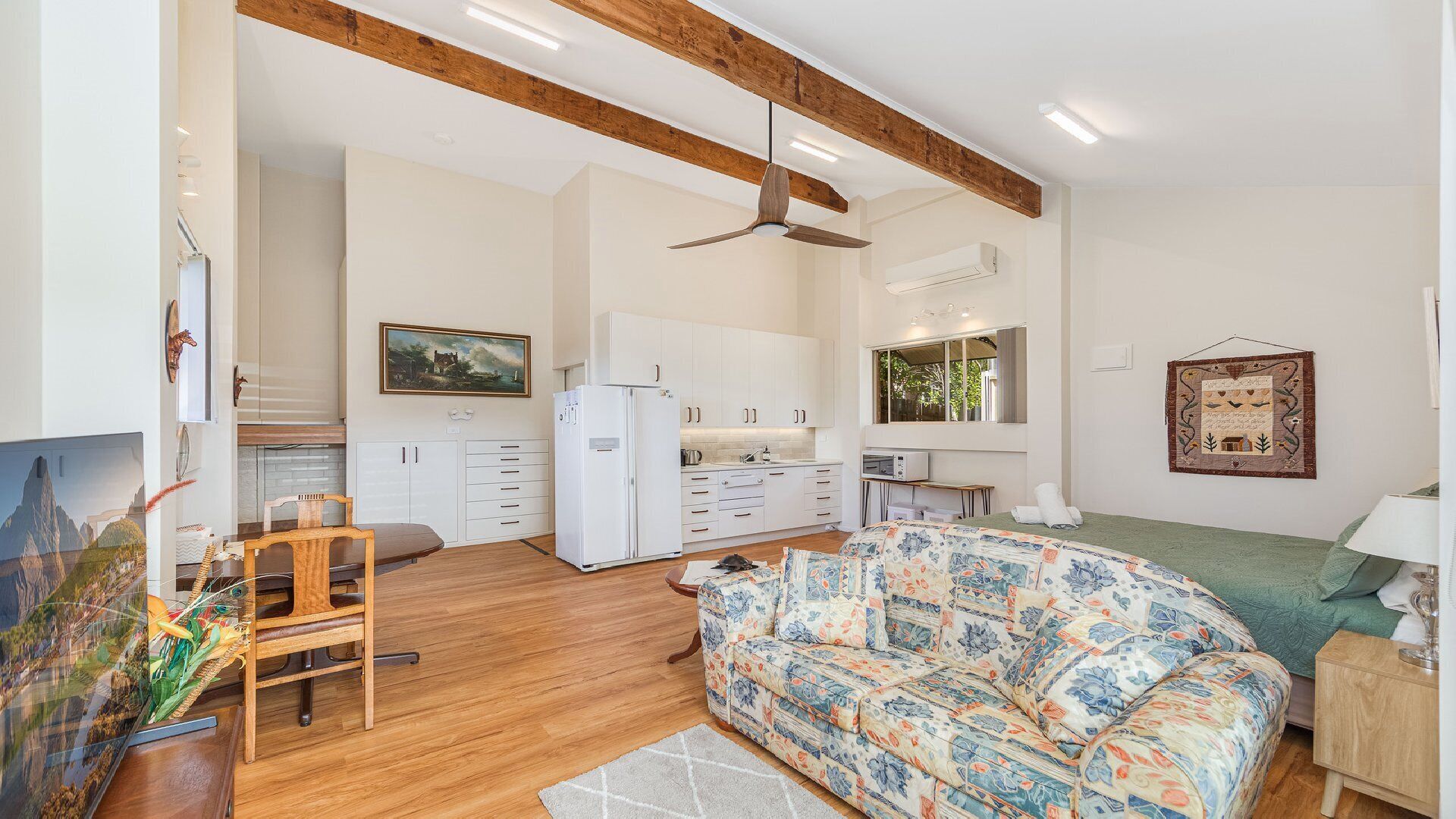 A modern interior with a wooden ceiling, a sofa, a dining table, and a kitchen area.
