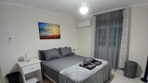 Ein Schlafzimmer mit einem Bett, Nachttischen, einem Mülleimer und einem Gemälde an der Wand.