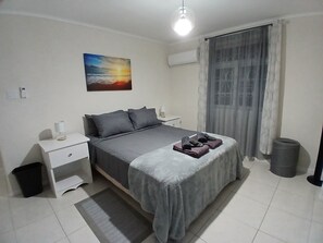 Ein Schlafzimmer mit einem Bett, Nachttischen, einem Mülleimer und einem Gemälde an der Wand.