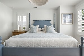 Ein Schlafzimmer mit einem Bett, einem Nachttisch, einer Lampe und einem gerahmten Bild an der Wand.