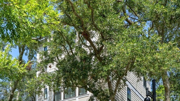 A two-story house with a garage, surrounded by mature trees and a well-maintained lawn. - Sully & Sonshine | 3 BR Near Sullivan's Island (Mount Pleasant)