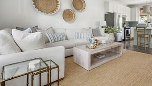 A modern living room with a sofa, coffee table, and decorative items. - Sully & Sonshine | 3 BR Near Sullivan's Island (Mount Pleasant)