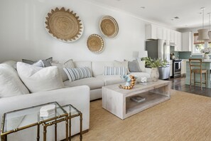 A modern living room with a sofa, coffee table, and decorative items. - Sully & Sonshine | 3 BR Near Sullivan's Island (Mount Pleasant)