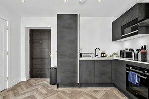 A modern kitchen with a built-in fridge, a microwave, and a stove. - Cozy King Bed Flat | Kitchen and Nature Views | London | 2 Min Tube | Sleeps 3 (Barnet)