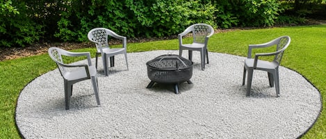 A circular outdoor seating area with a fire pit and four chairs.