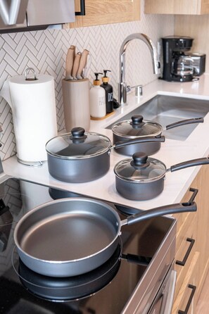 Une cuisine équipée d’une cuisinière, de casseroles, d’une poêle, d’une machine à café et d’un évier.