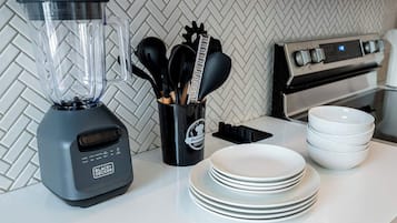 Een keuken met een blender, een keukengerei-houder en een stapel borden.