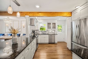 A modern kitchen with white cabinetry, stainless steel appliances, and a wooden ceiling beam. - Entire home in Seminole, Florida, United States (Seminole)