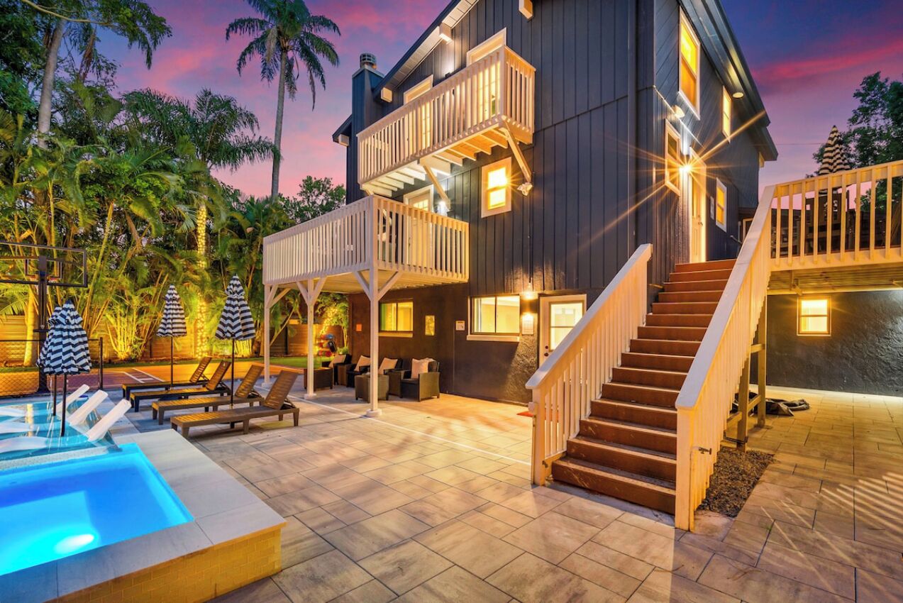 Une maison à deux étages avec une piscine, un espace salon extérieur et un escalier.