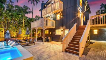 A two-story house with a pool, outdoor seating, and a staircase.