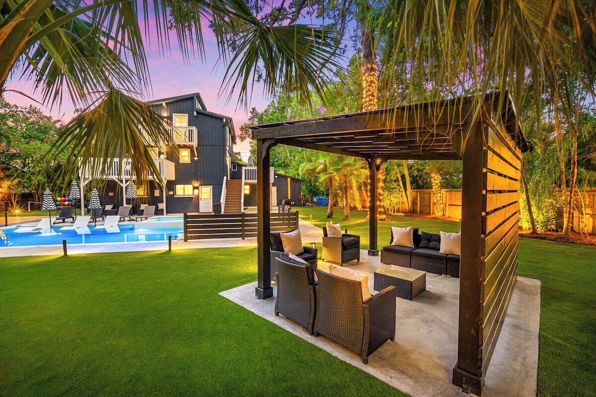 A backyard with a swimming pool, outdoor seating, and a covered patio area.