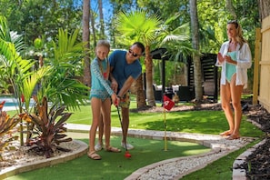 A person playing mini-golf in a garden with tropical plants and a small pool. - Entire home in Seminole, Florida, United States (Seminole)