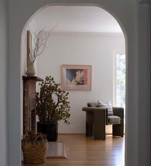 Ein Zimmer mit Kamin, einer Topfpflanze, einem gerahmten Bild an der Wand und einem Sofa.