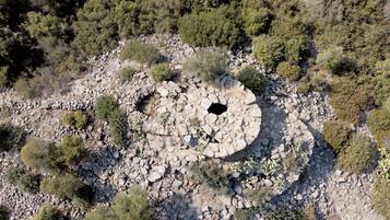 An aerial view of a circular stone structure surrounded by sparse vegetation.