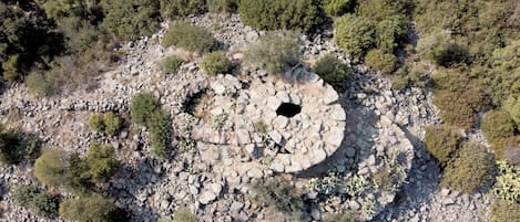 An aerial view of a circular stone structure surrounded by sparse vegetation.