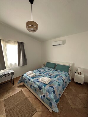 Ein Schlafzimmer mit Bett, Nachttischen, einem Schreibtisch und einer Pendelleuchte.
