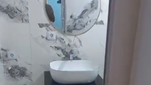 A bathroom with a white sink, a mirror, and a wall with a floral pattern.