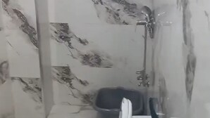 A bathroom with a toilet, a blue basin, and a shower area.