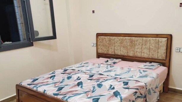 A single bed with a wooden frame and a headboard with a patterned fabric.