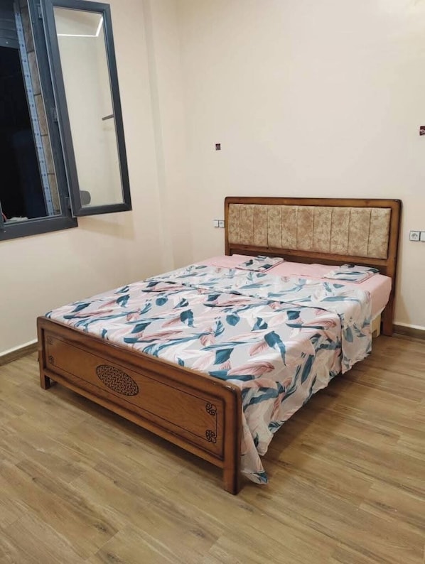 A single bed with a wooden frame and a headboard with a patterned fabric.