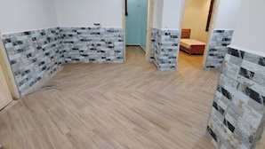 A room with a wooden floor, white walls, and a door leading to another room.