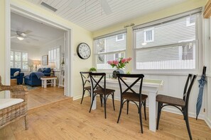A dining area with a table and chairs, a clock on the wall, and a view of the outside through large windows. - Walk Downtown & Waterfront | Dunedin's Best Street (Dunedin)