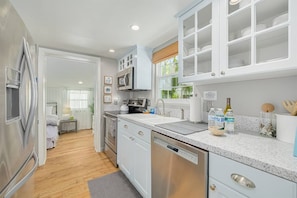 A modern kitchen with stainless steel appliances, white cabinetry, and a granite countertop. - Prized Dunedin St | Walk Downtown & Waterfront (Dunedin)