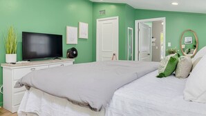 Un dormitori amb llit, televisió, petaca i una porta que dona a una altra habitació.