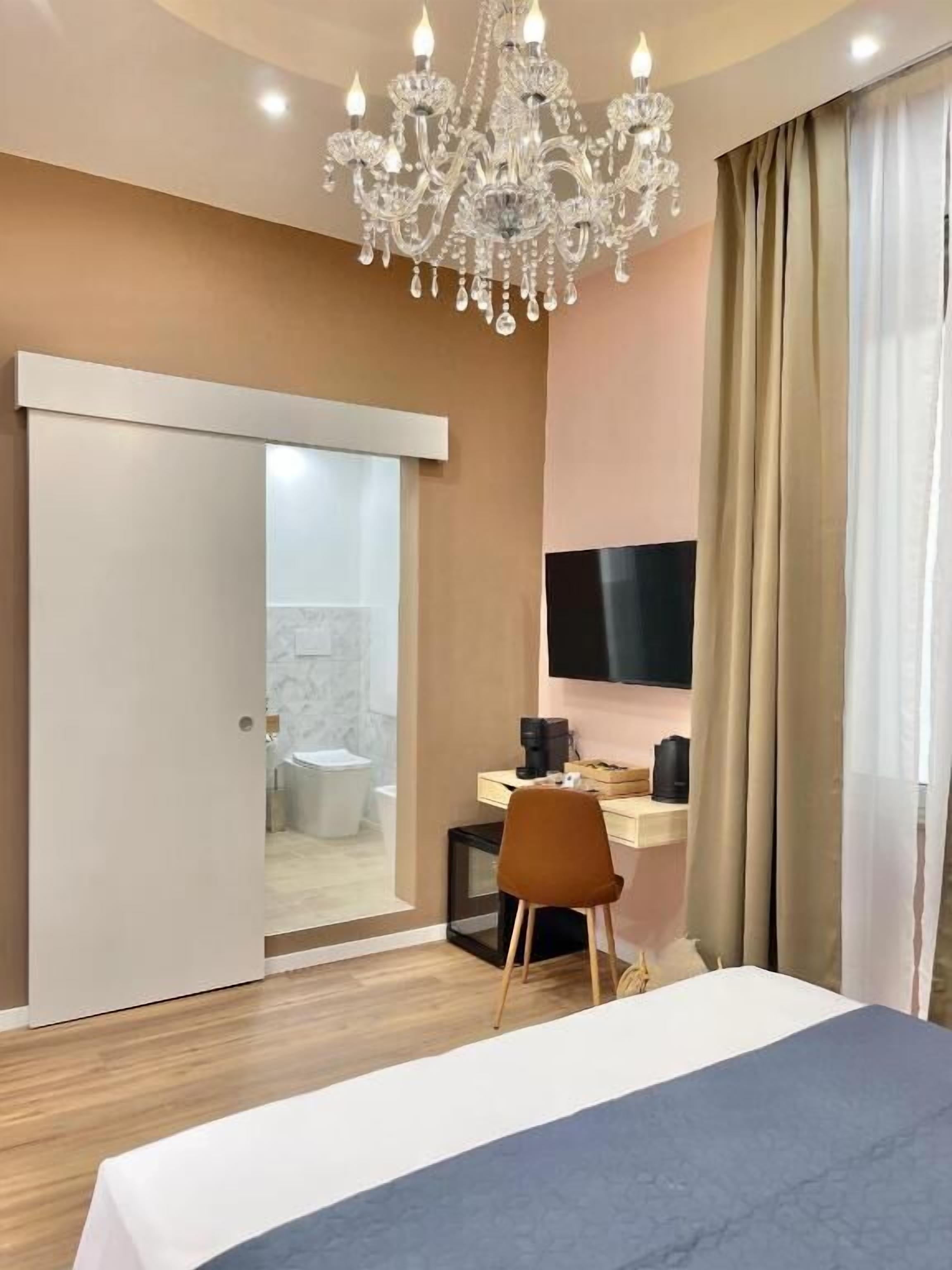 Una habitación de hotel con una cama, un escritorio, una silla, un televisor y una araña.