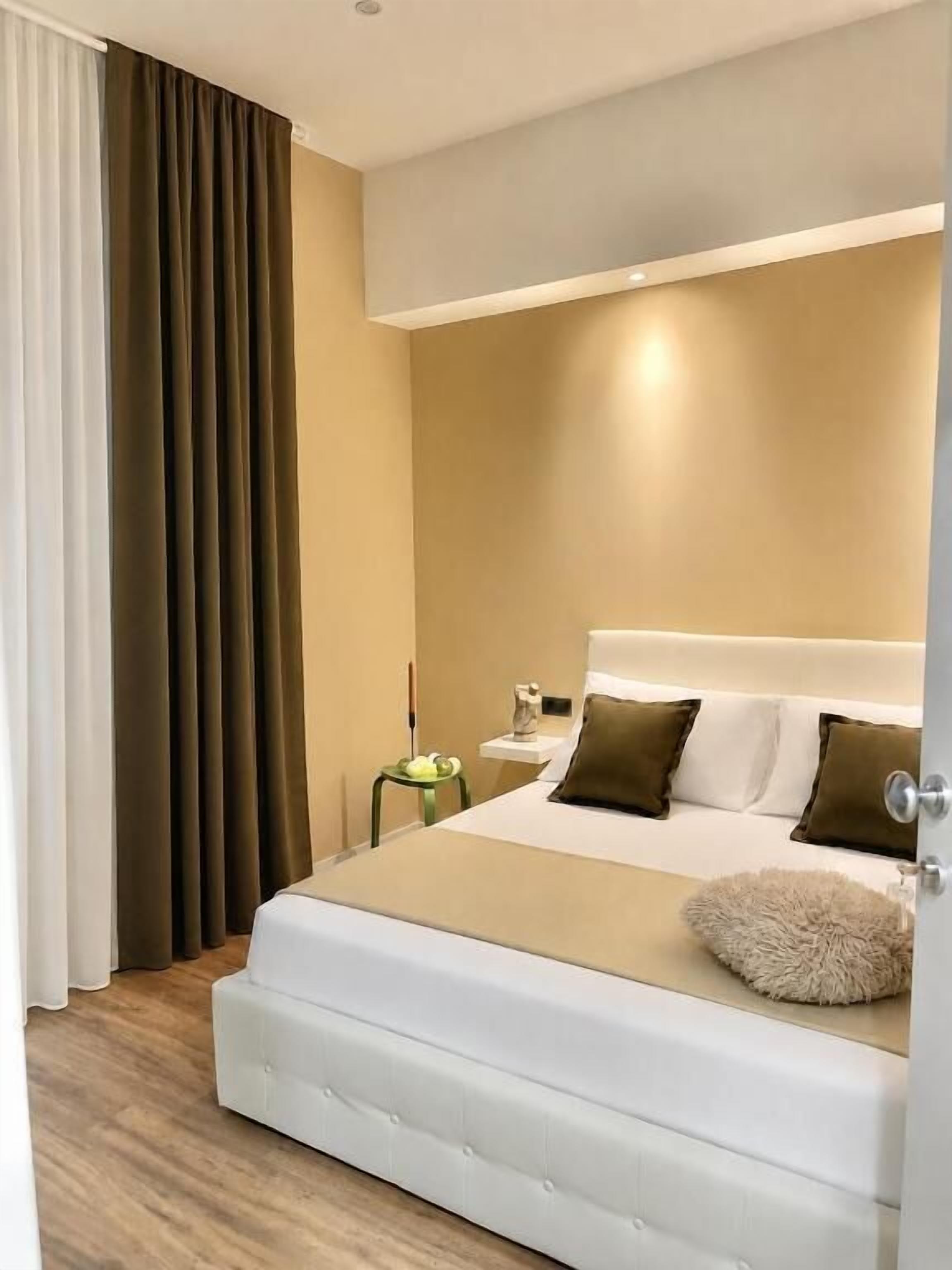 A modern hotel room with a large bed, a bedside table, and a nightstand.