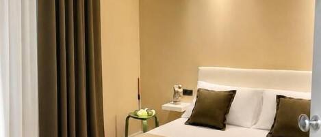 A modern hotel room with a large bed, a bedside table, and a nightstand.