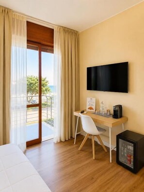 Una habitación de hotel con cama, un escritorio con silla, televisión y refrigerador.