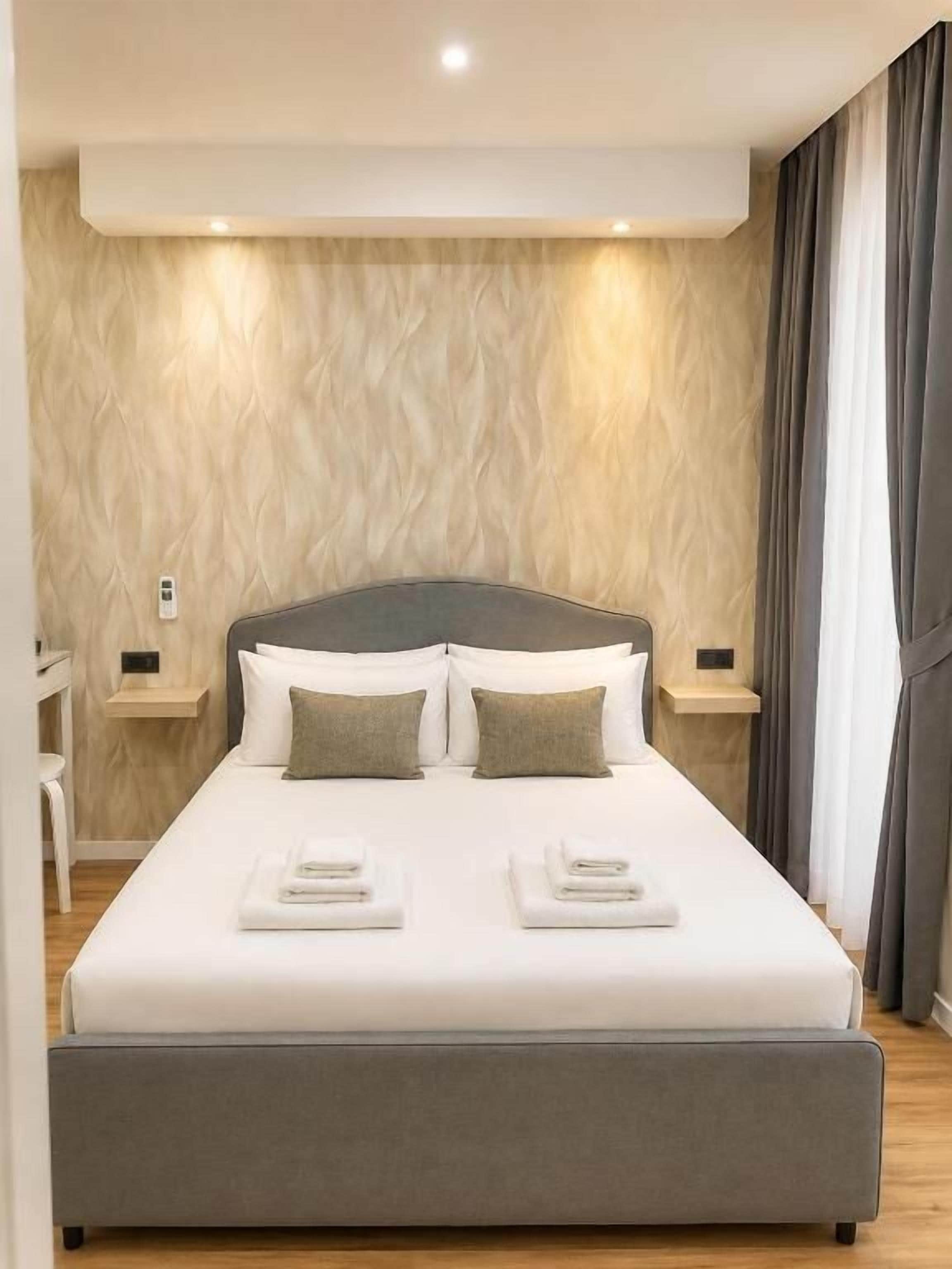 Ein modernes Hotelzimmer mit einem großen Bett, Nachttischen und einer Wand mit Holzstruktur.