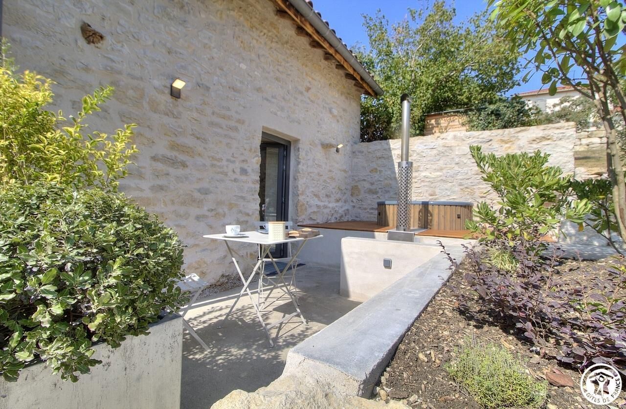 A stone building with a small patio area, a table, and a bench.