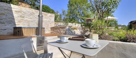Un espacio al aire libre con pared de piedra, una parrilla metálica y vistas a la aguja de una iglesia.