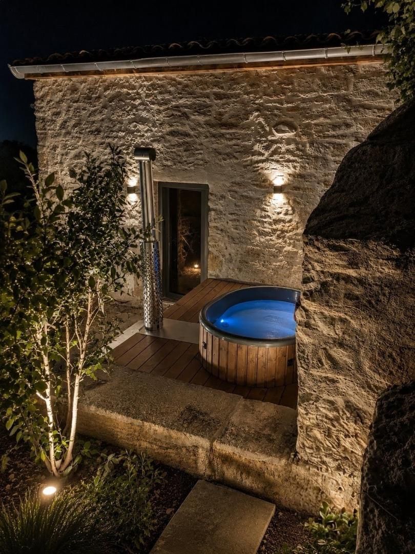 A stone building with a hot tub and a door leading to an interior space.