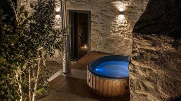 A stone building with a hot tub and a door leading to an interior space.