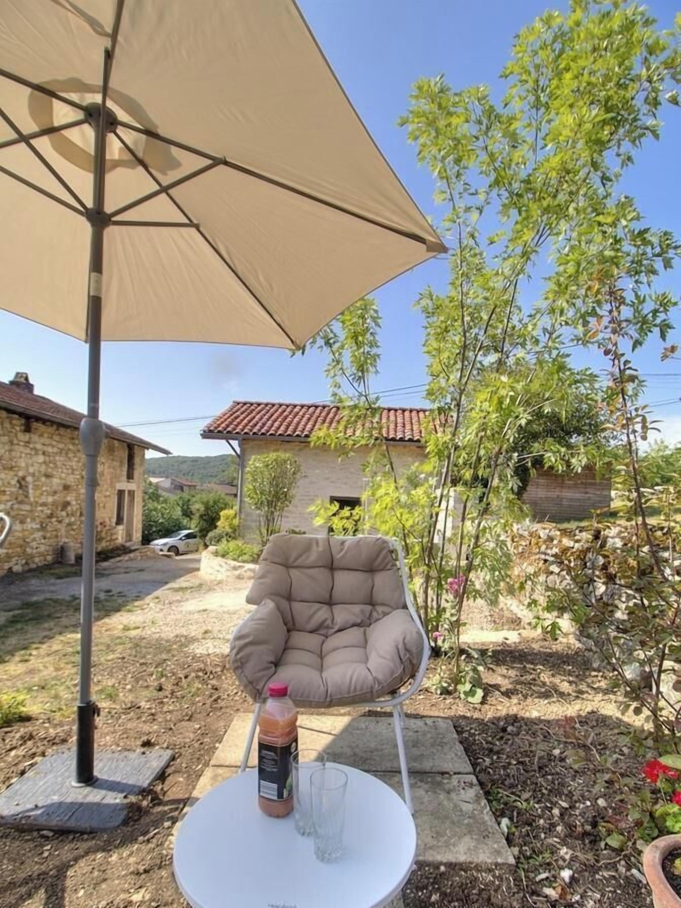 Een buitenruimte met een tafel, stoel en parasol.