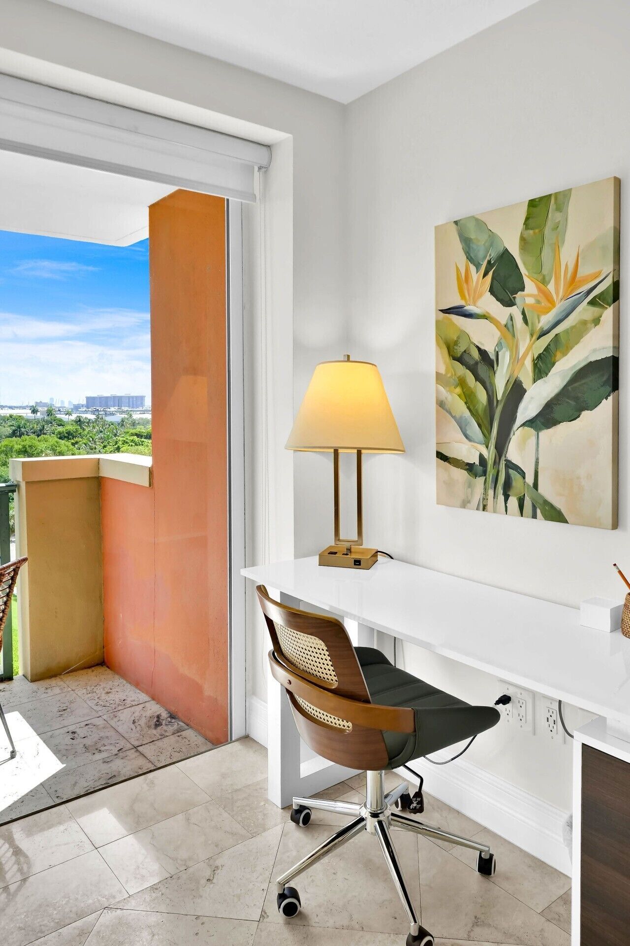 A modern office space with a desk, chair, lamp, and artwork.