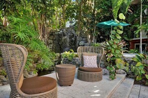 Wicker furniture with cushions in an outdoor setting with a rock wall and tropical plants. - Modern Bay View Balcony in the Grove Free Parking (Miami)