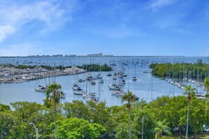 A marina with numerous boats docked, surrounded by lush greenery and a clear sky. - Modern Bay View Balcony in the Grove Free Parking (Miami)
