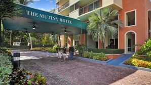 Der Eingang des Mutiny Hotel mit einer überdachten Passage, Palmen und einem Ziegelweg.