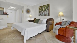 Ein Hotelzimmer mit Bett, Sofa, Sessel, einem Gemälde und einer Lampe.