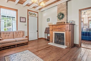 Ein gemütliches Wohnzimmer mit Holzboden, Kamin, Sofa und Teppich.