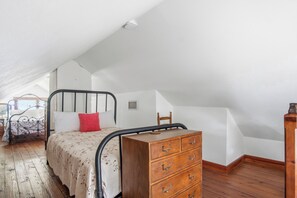 Ein Schlafzimmer mit einem Bett, einer Holzkommode und einer schrägen Decke.