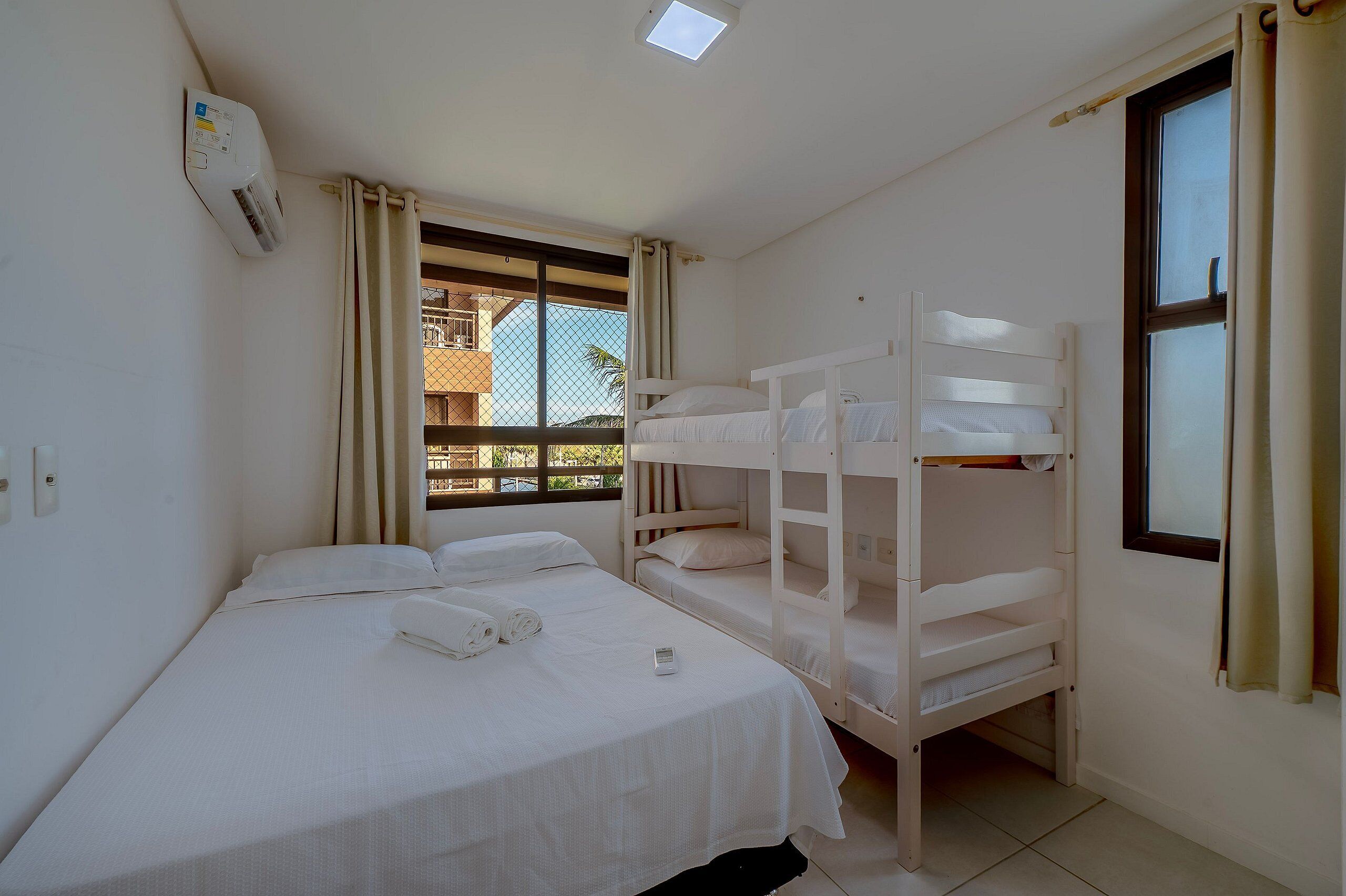 Una habitación con literas, una ventana con cortinas y un equipo de aire acondicionado.