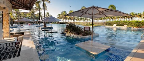 A swimming pool with lounge chairs and umbrellas, surrounded by palm trees.