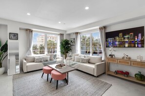 A modern living room with a sofa set, a coffee table, and a cityscape view. - South Beach 1BR on Ocean Drive · Steps to the Sand (Miami Beach)